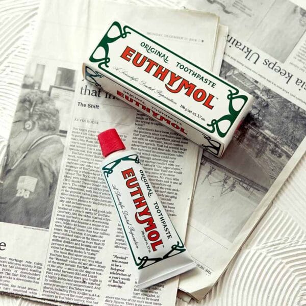 Euthymol Original Zahnpasta – Fluoridfreie Mundpflege mit einzigartigem Geschmack und rosa Farbe. Produkt Abbildung Zahnpasta auf Zeitung