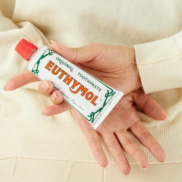 Euthymol Original Zahnpasta – Fluoridfreie Mundpflege mit einzigartigem Geschmack und rosa Farbe. Produkt Abbildung Zahnpasta hinter dem Rücken