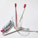 Euthymol Whitening Zahnbürste – Weisse Handzahnbürste mit Flex-Firm-Technologie für sanfte Plaque-Entfernung. Abbildung Zahnbürsten im Glas mit Zahnpasta.