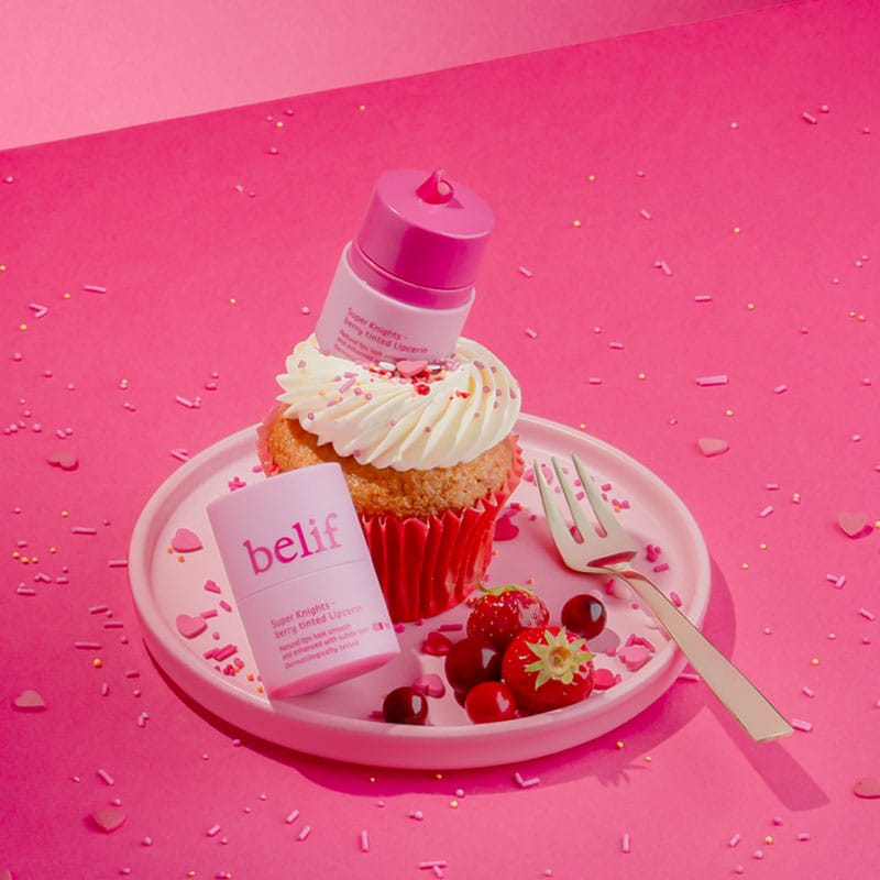 belif Multi Vitamin Pink Lipcerin 15ml – Pflegender Lippenbalsam & Maske mit pinkem Farbton, Cranberry-Erdbeer-Aroma und Multi-Vitamin-Komplex. Abbildung Lippenbalsam mit Cupcake und Beeren.