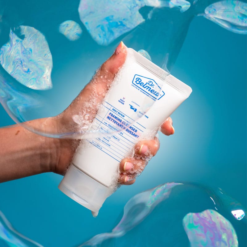Dr. Belmeur Daily Repair Foaming Cleanser 150ml - mousse nettoyante douce au pH équilibré, à l'extrait de bouleau et au panthénol, pour les peaux sensibles. Illustration produit en main avec mousse.