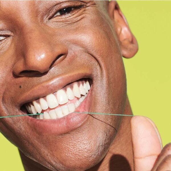 18230992 REACH POP Dental Floss Peppermint Floss - vegan, waxed dental floss with 384 micro threads & sustainable packaging, 50m, peppermint flavor. Picture dental floss in action. 